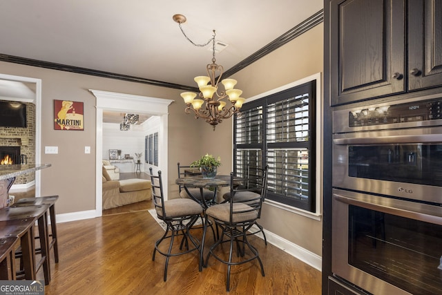 dining area featuring dark wood-style floors, a fireplace, baseboards, and crown molding