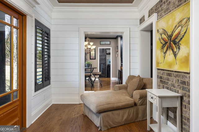 sitting room featuring a chandelier, dark wood-style flooring, crown molding, and baseboards