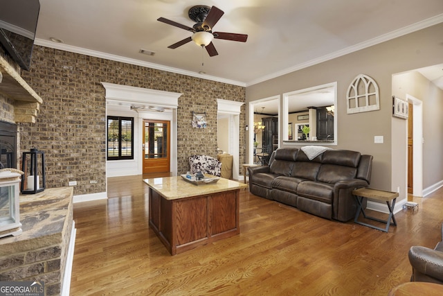 living room featuring crown molding, visible vents, a glass covered fireplace, ceiling fan, and wood finished floors