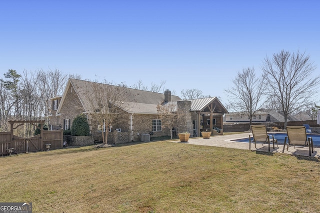 back of property featuring a fenced in pool, a fenced backyard, a chimney, a yard, and a patio area