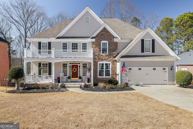 view of front facade with covered porch, a front yard, a balcony, stone siding, and driveway