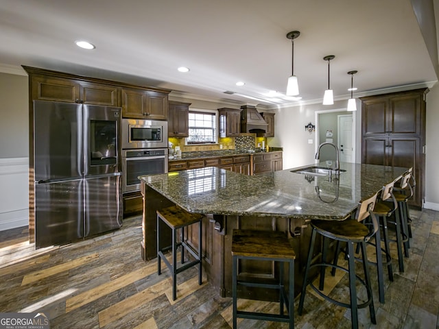 kitchen featuring dark brown cabinetry, crown molding, a sink, appliances with stainless steel finishes, and custom range hood