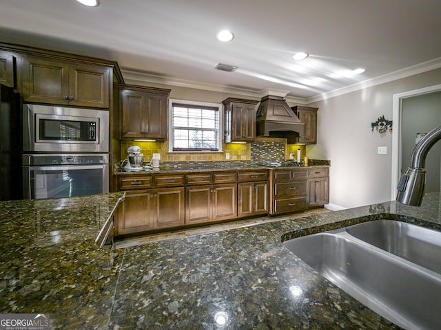 kitchen featuring stainless steel appliances, a sink, visible vents, custom range hood, and crown molding