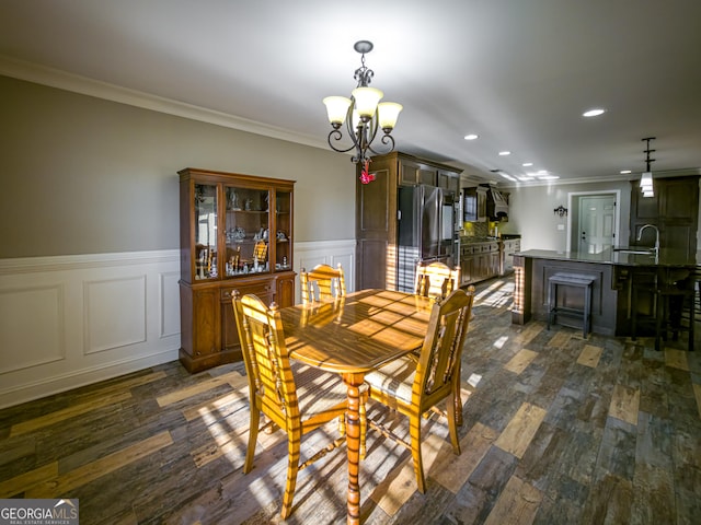 dining space with a wainscoted wall, ornamental molding, dark wood-type flooring, a notable chandelier, and recessed lighting