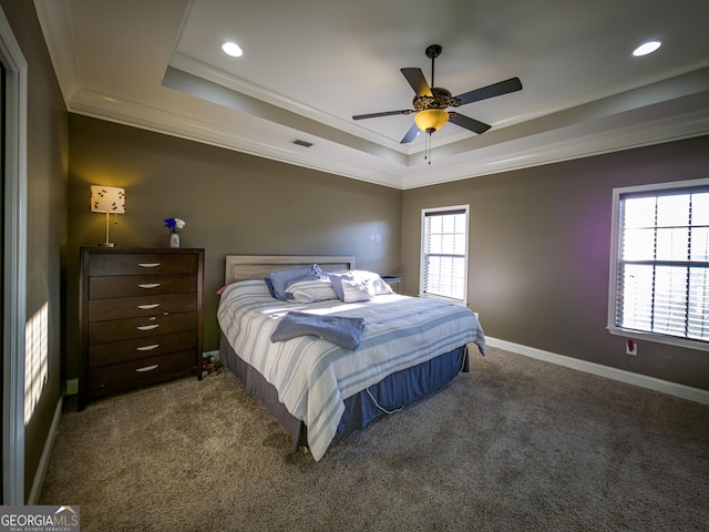 carpeted bedroom with baseboards, visible vents, a tray ceiling, and crown molding