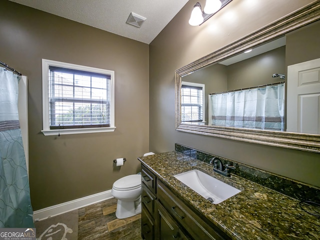 bathroom with visible vents, toilet, vanity, a textured ceiling, and baseboards