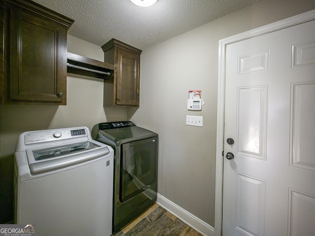 laundry room with a textured ceiling, dark wood-style flooring, baseboards, independent washer and dryer, and cabinet space