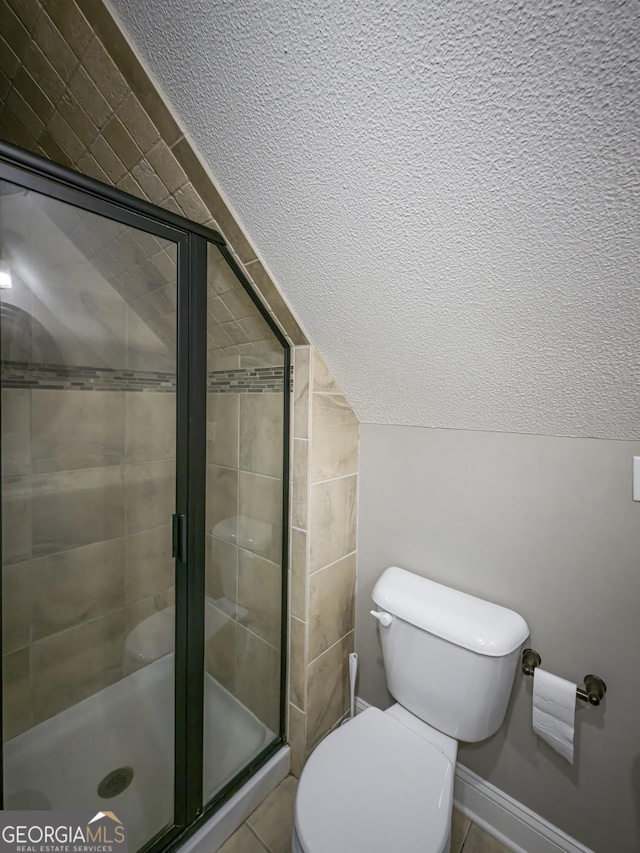 bathroom with toilet, a shower stall, and vaulted ceiling