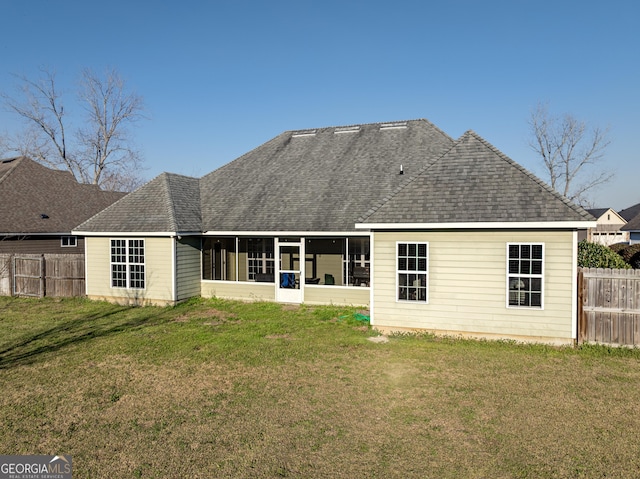 back of property featuring a sunroom, fence, a lawn, and roof with shingles