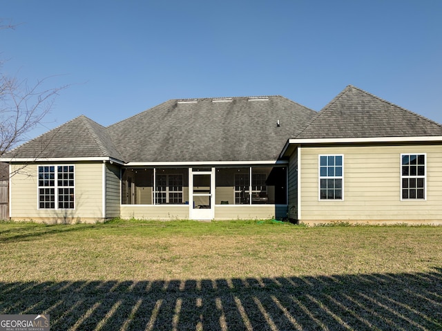 back of house featuring a shingled roof, a lawn, and a sunroom