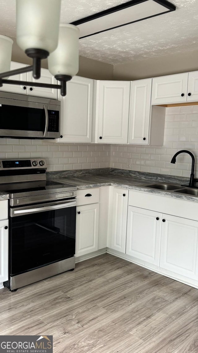 4778 Pebble Trce, Buford, GA 30518 - kitchen featuring stainless steel appliances, tasteful backsplash, a sink, and white cabinets