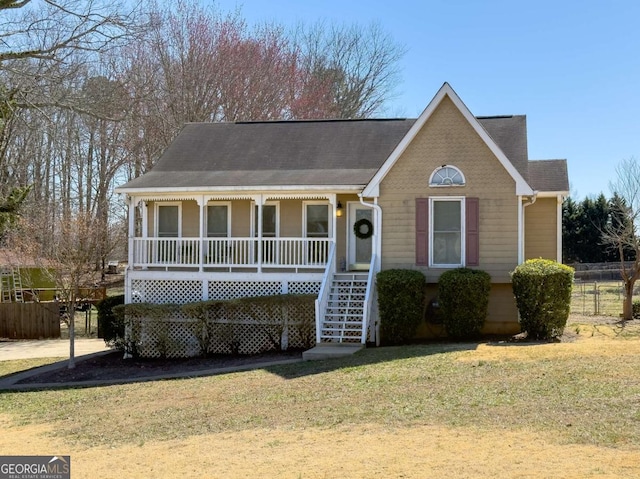 view of front of property with covered porch, a front lawn, and fence