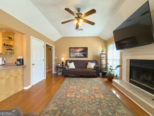 living room with lofted ceiling, a fireplace, wood finished floors, visible vents, and baseboards