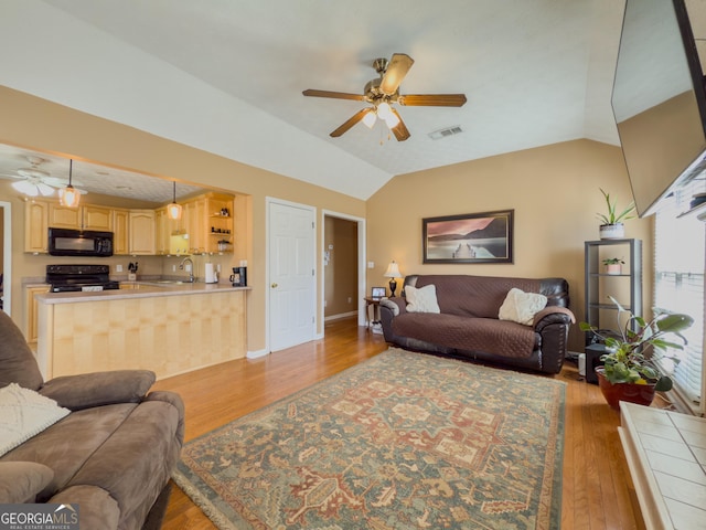 living room featuring ceiling fan, visible vents, vaulted ceiling, and wood finished floors