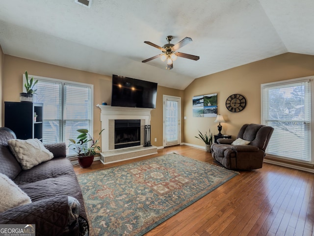 living area with a healthy amount of sunlight, vaulted ceiling, and hardwood / wood-style floors