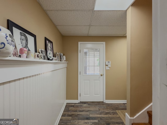 doorway to outside with dark wood finished floors, a paneled ceiling, and baseboards