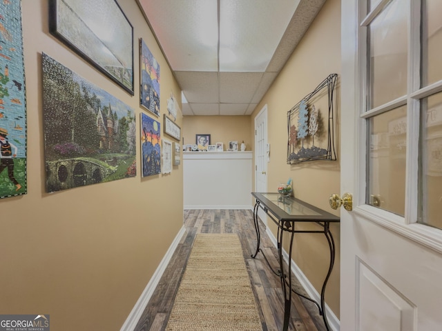 hall with baseboards, a drop ceiling, and wood finished floors