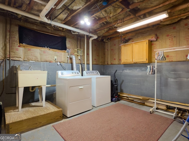 clothes washing area with concrete block wall, cabinet space, and separate washer and dryer