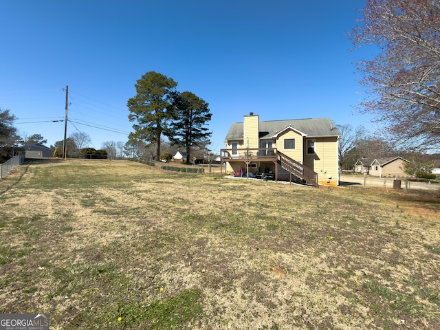 view of yard with fence, a wooden deck, and stairs