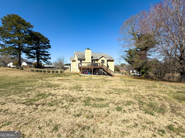 back of property featuring a yard, a chimney, stairway, fence, and a wooden deck