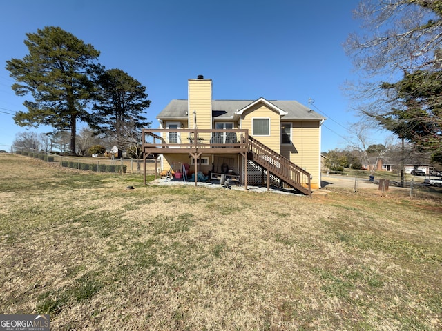 rear view of property featuring a chimney, a lawn, stairway, fence, and a deck