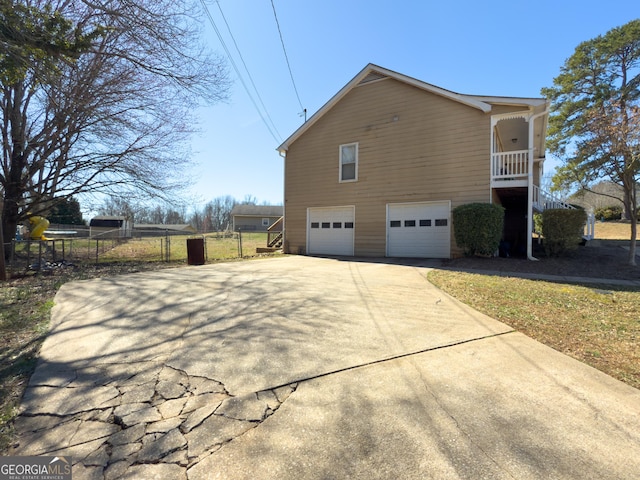 view of home's exterior featuring a garage, driveway, and fence