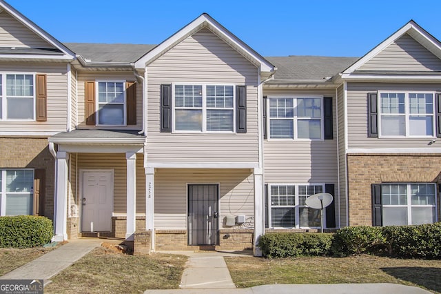 multi unit property with a shingled roof and brick siding