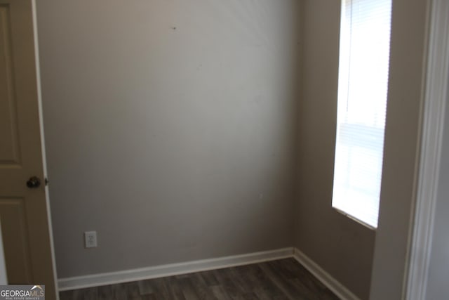 empty room featuring dark wood-type flooring, a wealth of natural light, and baseboards