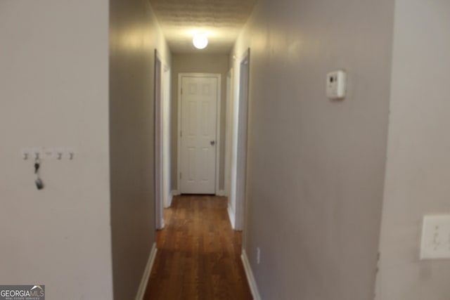 hall with dark wood-style floors and baseboards