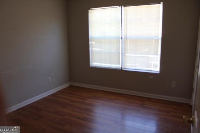 unfurnished room with wood finished floors, a wealth of natural light, and baseboards