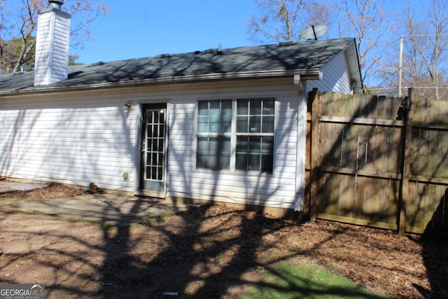 view of side of home with a chimney and fence