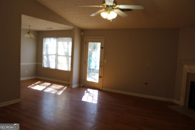 unfurnished living room with wood finished floors, a fireplace with flush hearth, a ceiling fan, vaulted ceiling, and baseboards