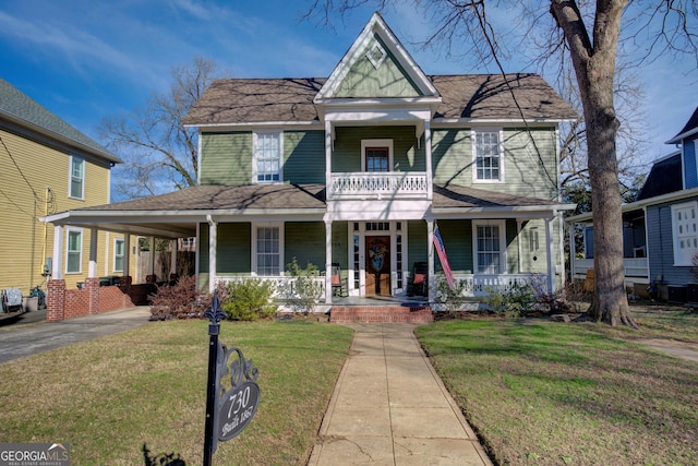 victorian home with a porch, an attached carport, a balcony, driveway, and a front yard