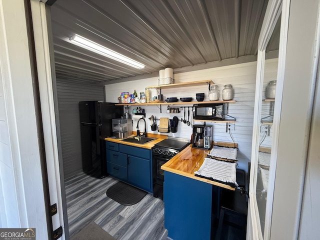 kitchen featuring blue cabinetry, open shelves, butcher block counters, a sink, and black appliances