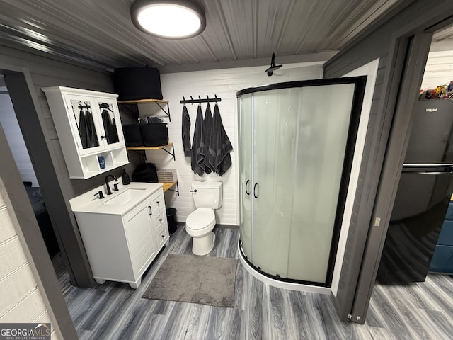 full bathroom with toilet, wood finished floors, vanity, and a shower stall