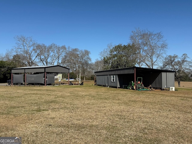 view of yard with a detached carport, a pole building, and an outbuilding