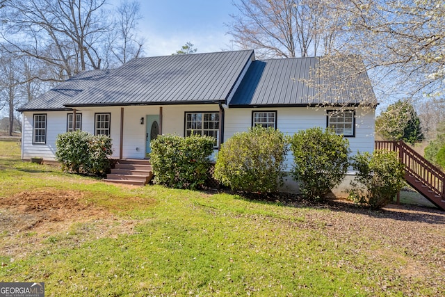 single story home featuring covered porch, metal roof, and a front yard