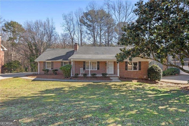 ranch-style home featuring brick siding, a chimney, and a front yard