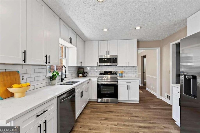 kitchen with visible vents, wood finished floors, stainless steel appliances, white cabinetry, and a sink