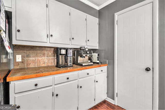 kitchen with white cabinets, ornamental molding, decorative backsplash, and dark wood-type flooring