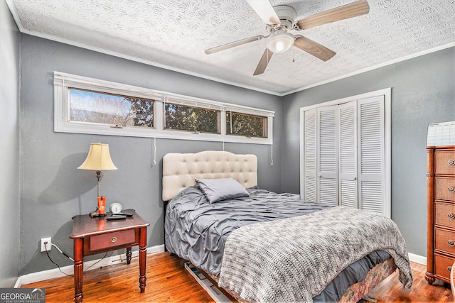 bedroom featuring a closet, wood finished floors, ornamental molding, a textured ceiling, and multiple windows