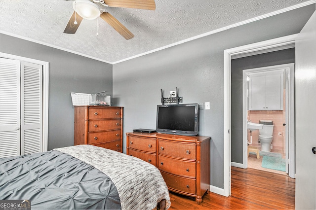 bedroom featuring wood finished floors, ornamental molding, a textured ceiling, a closet, and a ceiling fan