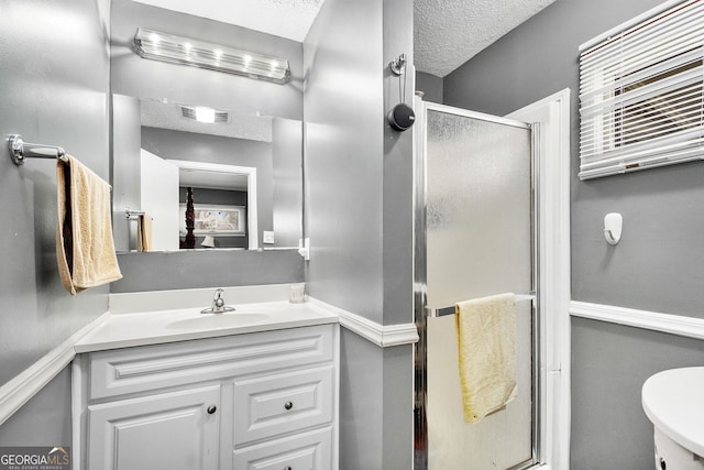 bathroom with a stall shower, vanity, toilet, and a textured ceiling