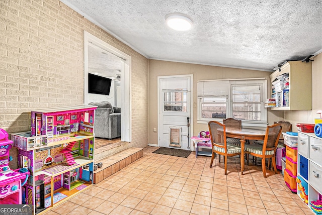 recreation room featuring tile patterned floors, brick wall, lofted ceiling, and a textured ceiling