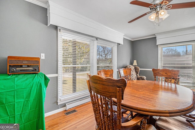 dining area featuring ceiling fan, baseboards, crown molding, light wood-type flooring, and a baseboard heating unit