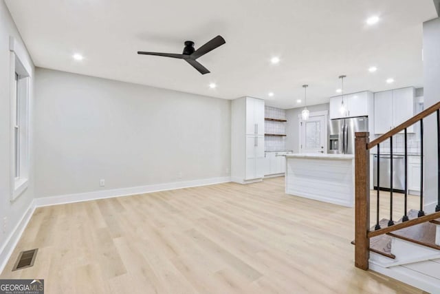 unfurnished living room with light wood finished floors, stairs, and visible vents