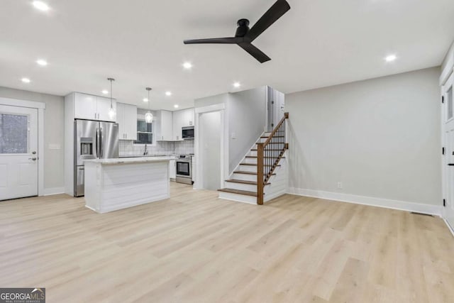 kitchen with stainless steel appliances, tasteful backsplash, light countertops, a kitchen island, and light wood-type flooring