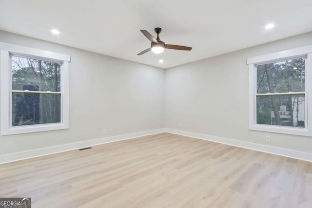 unfurnished room with light wood finished floors, plenty of natural light, and baseboards