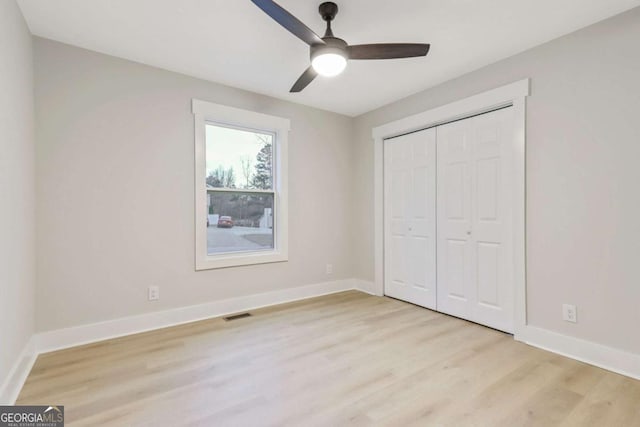 unfurnished bedroom featuring visible vents, baseboards, a ceiling fan, light wood-type flooring, and a closet