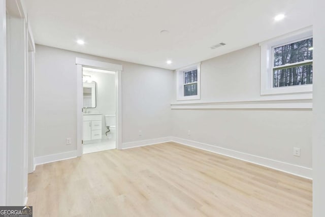 finished below grade area with recessed lighting, light wood-type flooring, visible vents, and baseboards